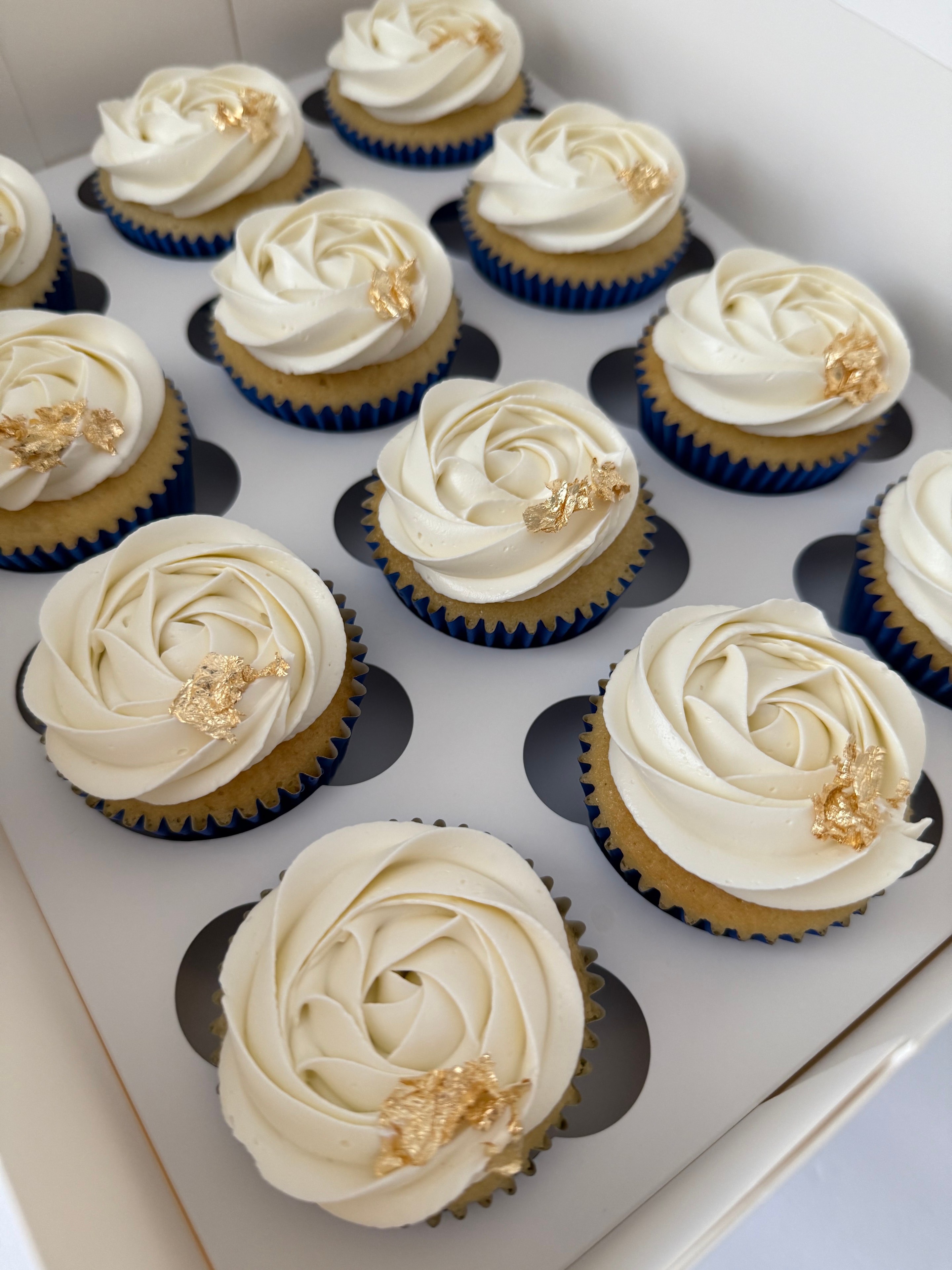 Vanilla cupcakes with ivory rose frosting and gold leaf accents